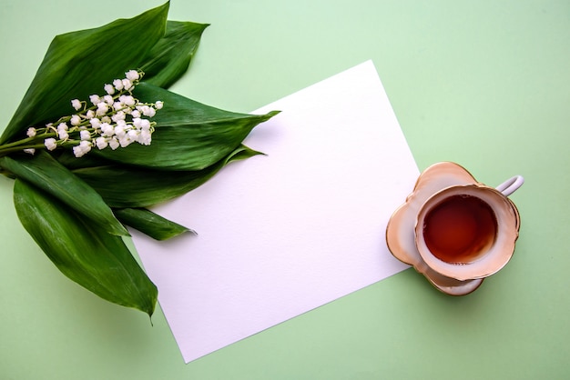 Boeket van lelietje-van-dalen, een kopje thee en een vel papier