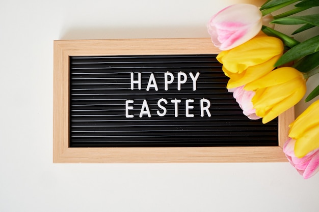 Boeket van lentetulpen en bord met de inscriptie Happy Easter