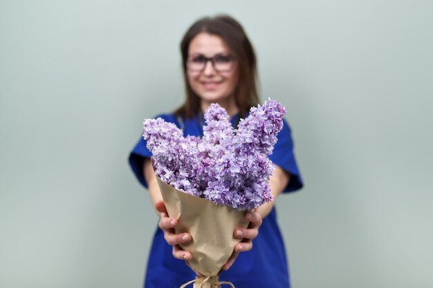 Boeket van lila bloemen in de handen van vrouwelijke arts. Viering, cadeau, respect en liefde, lichtgroene achtergrond