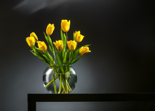 Boeket van mooie verse gele tulpen in dauw op donkere achtergrond. Stilleven foto