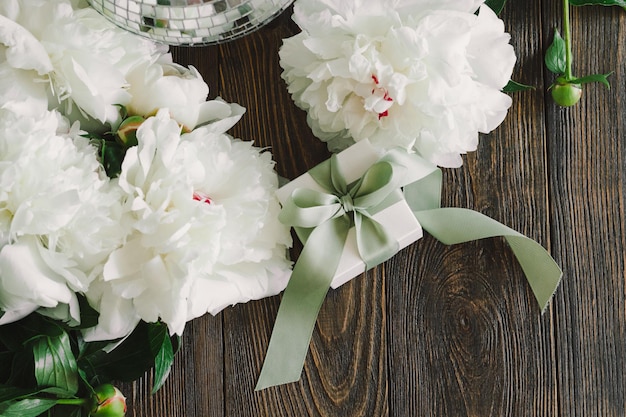 Boeket van mooie witte pioenrozen met geschenkdozen op houten achtergrond Stijlvolle bloemengroeten Moederdag