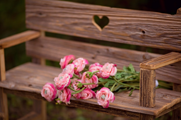 Boeket van ranonkelbloemen op een oude houten bank op de zomeraard