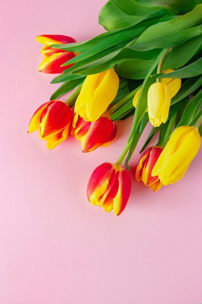 Boeket van rode en gele tulpen op pastelroze achtergrond Lente symbool vakantie cadeau Plaats voor tekst