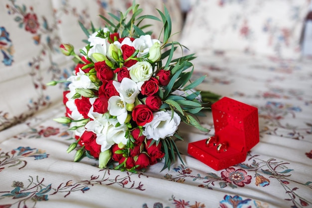 Boeket van rode en witte rozen bloemen op de bank met trouwringen