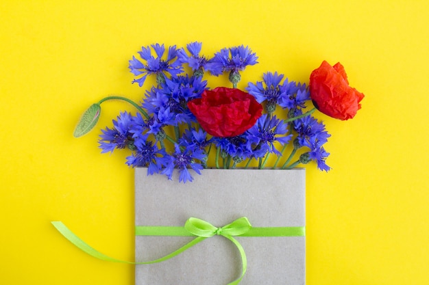 Boeket van rode papavers en blauwe korenbloemen in een gebonden envelop