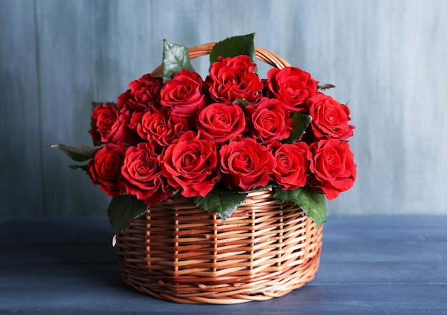 Boeket van rode rozen in mand op houten achtergrond