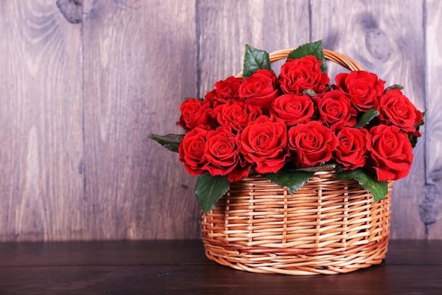 Boeket van rode rozen in mand op houten achtergrond
