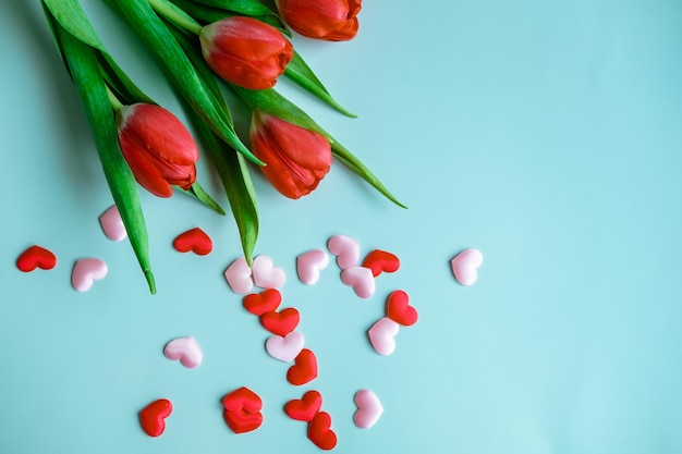 Boeket van rode tulpen met kleine hartjes op een blauwe achtergrond bovenaanzicht