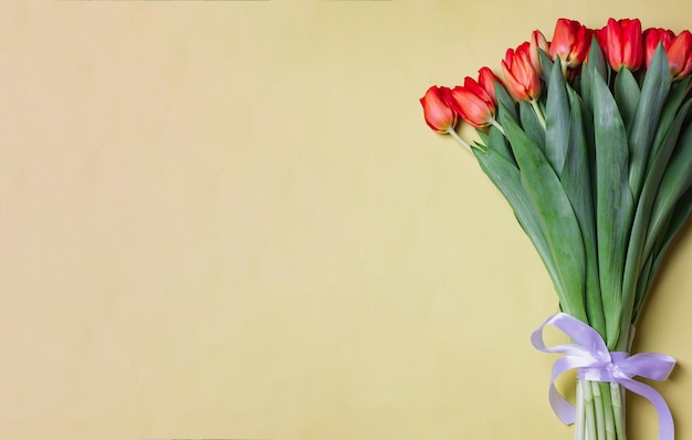 Boeket van rode tulpen op lichtgele achtergrond flatlay met copyspace