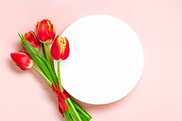 Boeket van rode tulpen wit podium op roze achtergrond Bovenaanzicht Plat lag vakantie wenskaart