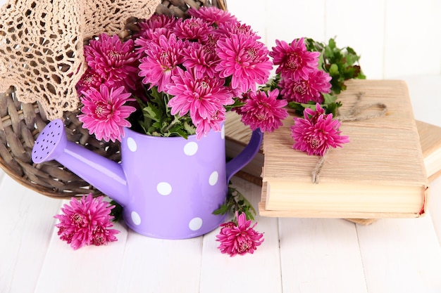 Boeket van roze chrysant in gieter op witte houten achtergrond