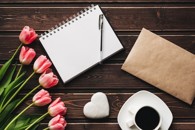 Boeket van roze tulp bloemen en een kopje koffie op een houten bruine tafel