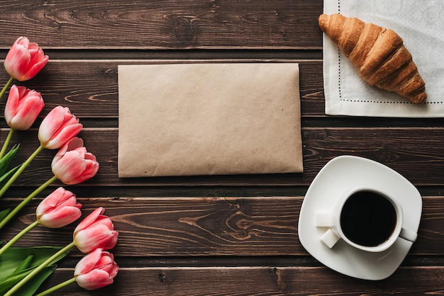 Boeket van roze tulpen met een kopje koffie en een croissant