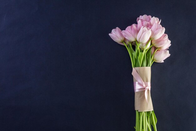 Boeket van roze tulpen op een zwarte achtergrond.