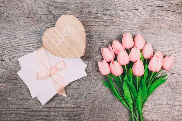 Boeket van tulpen en een envelop op een houten achtergrond, bovenaanzicht.