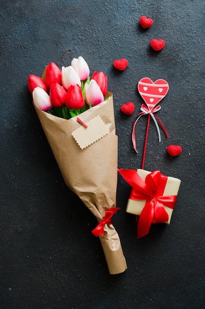 Foto boeket van tulpen en geschenkdoos op donkere achtergrond.