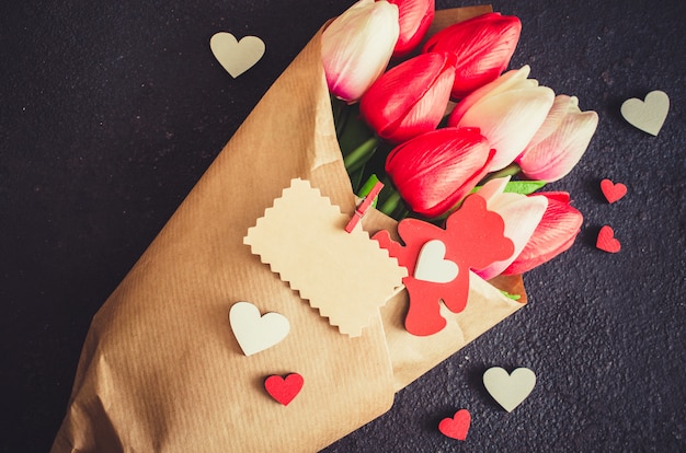 Boeket van tulpen en geschenkdoos op donkere achtergrond.