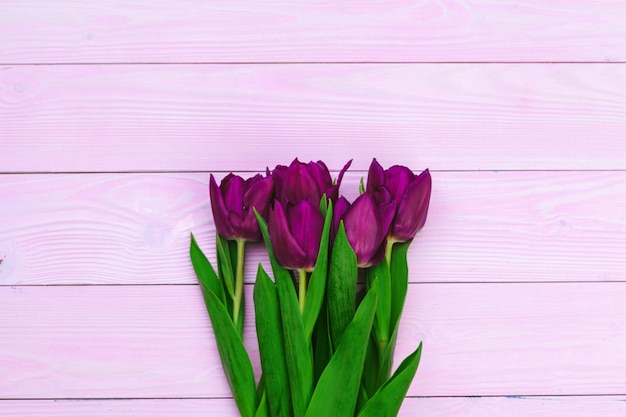 Boeket van tulpenbloemen op roze hout met exemplaarruimte