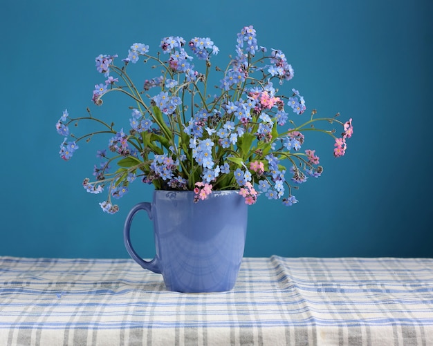 Boeket van vergeet-mij-nietjes op de tafel op een blauwe achtergrond.