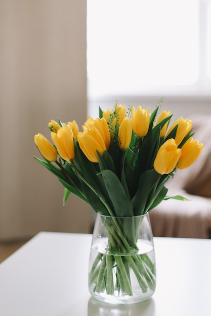 Boeket van verse gele tulpen op een tafel in de woonkamer interieur