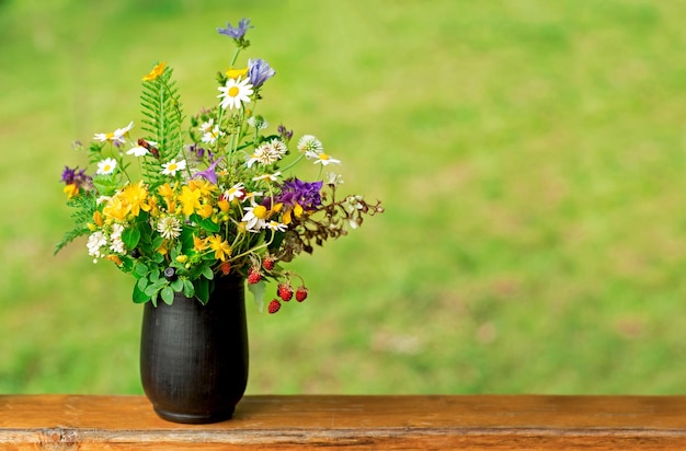 Boeket van wilde bloemen en aardbeienbessen staan op het terras