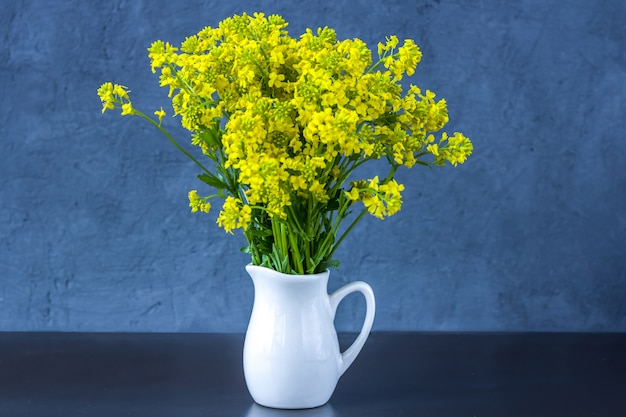 Boeket van wilde bloemen in een vaas op een donkerblauwe achtergrond. Verse Lentebloemen.