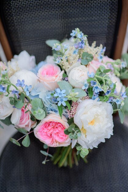 Boeket van witte en roze bloemen staat op grijze stoel op straat