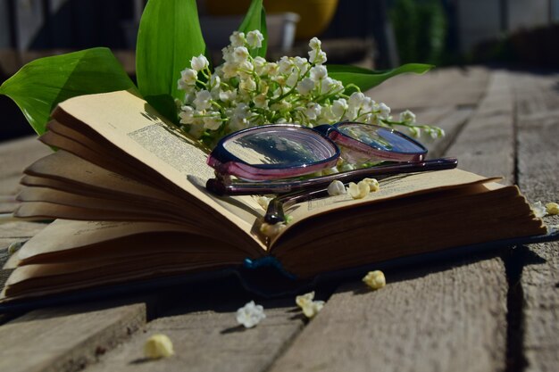 Boeket van witte lelietje-van-dalen met groen gebladerte op een boek met glazen houten backgrou