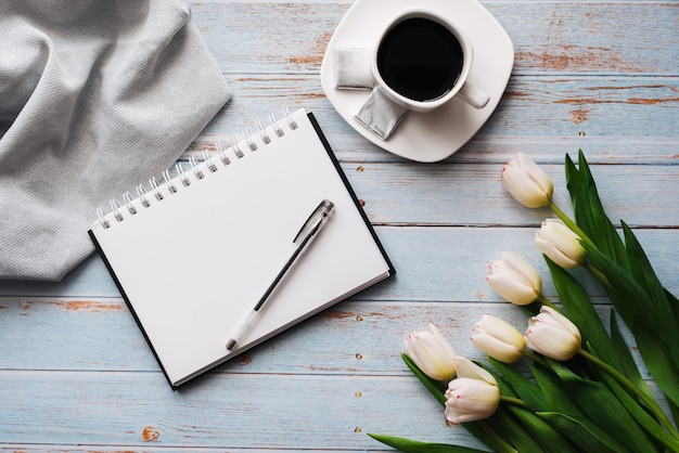 Boeket van witte tulpen met een lege laptop, een kopje koffie op een houten achtergrond