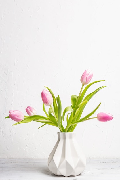 Boeket van zacht roze tulpen in een keramische vaas op witte achtergrond