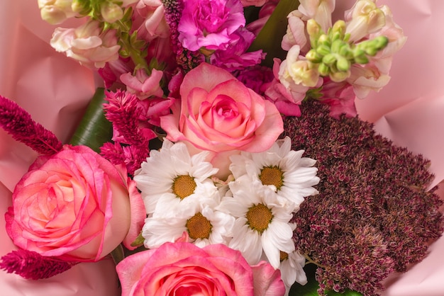 Boeket van zachtroze bloemen in roze cadeaupapier. Geïsoleerd op een witte achtergrond.