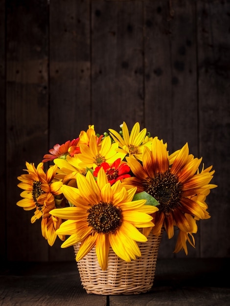 Boeket van zonnebloemen in mand op tafel over houten achtergrond