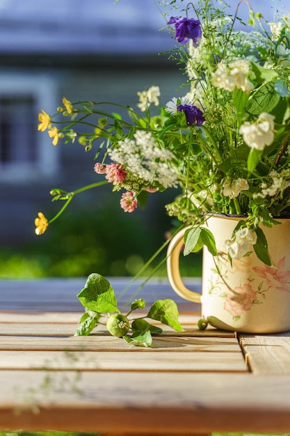 Foto boeket veldbloemen en een onrijpe groene appel op een tuintafel