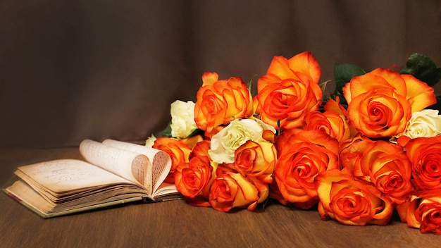 Boeket verse oranje rozen op tafel met een open boek