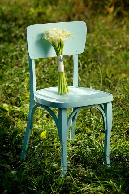 Boeket witte calla bloemen op blauwe stoel buitenshuis