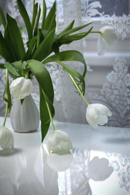 Boeket witte tulpen in een witte vaas op een witte tafel