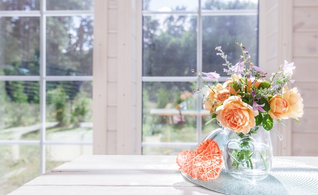 Boeket zomerrozen in glazen vaas bij het raam