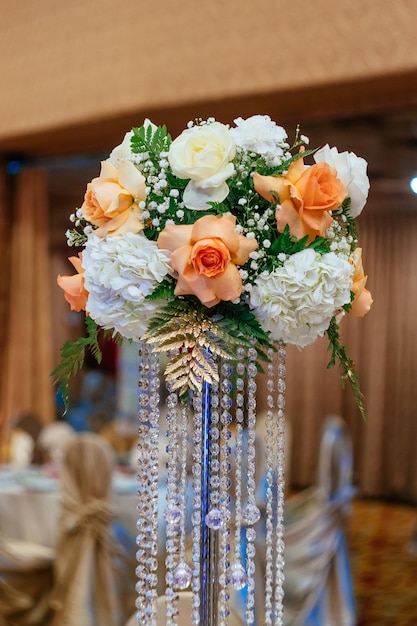 Boeketten van rozen op een feestelijke huwelijkslijst in de bloemen van het restauranthuwelijk en een lijst