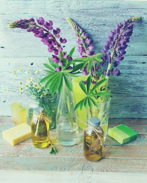 Boeketten van verse bloemen van paarse lupine natuurlijke zeep en aromatische oliën op een houten ondergrond