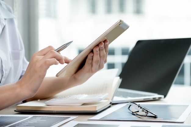 boekhouder gebruikt tablet en laptop die rekening houdt met het betalen van belasting op wit bureau in werkkantoor.
