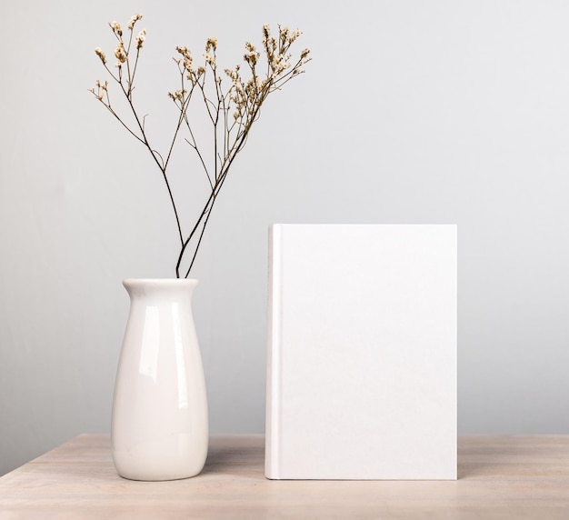 Boekmodel en gedroogde bloemen in vaas aan houten tafel Scandi-stijl Lezen hobby harmonie boekenwurm levensstijl concept Roman met blanco omslag