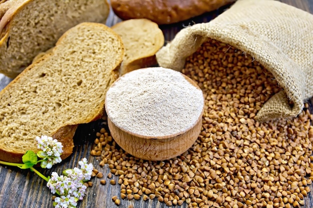 Boekweitmeel in een houten kom boekweit in de zak sneetjes brood boekweitbloem op de achtergrond van houten planken