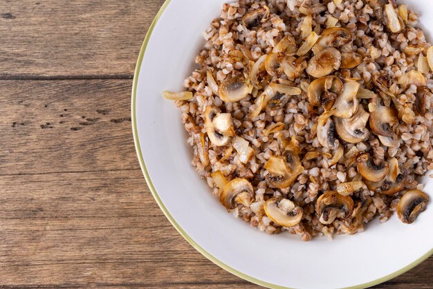 Boekweitpap met champignons in een witte plaat op houten ondergrond