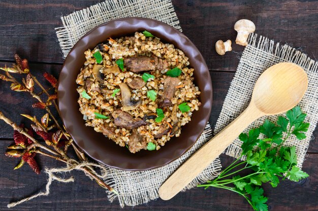 Boekweitpap met stukjes vlees en champignons op een donkere houten achtergrond