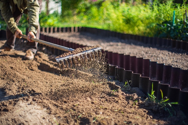 Boer cultiveert land in de tuin met handgereedschap Bodem losmaken Tuinconcept Landbouwwerkzaamheden op de plantage