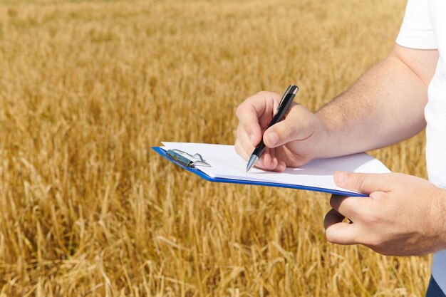 Foto boer inspecteert de oogst van de gerstplantage en maakt aantekeningen