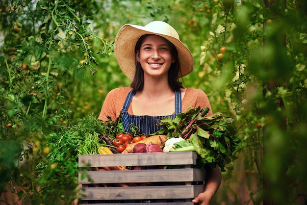 Boer landbouw en portret van vrouw met krat op boerderij na oogst van zomergroenten Landbouw vrouwelijke persoon en glimlach met doos groen product voedsel of agro in de natuur voor duurzaamheid