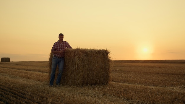 Boer lopen hooiberg veld bij gouden zonsondergang landelijk landschap Agro crop concept