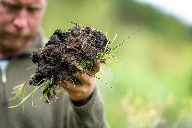 boer met een hoed die zonne-intelligent is met behulp van technologie en een tablet en telefoon in een veld die een bodem- en plantmonster in het veld bestudeert