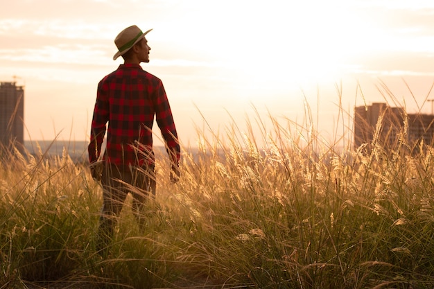 Boer met hoed in boerderij plantage op zonsondergang.